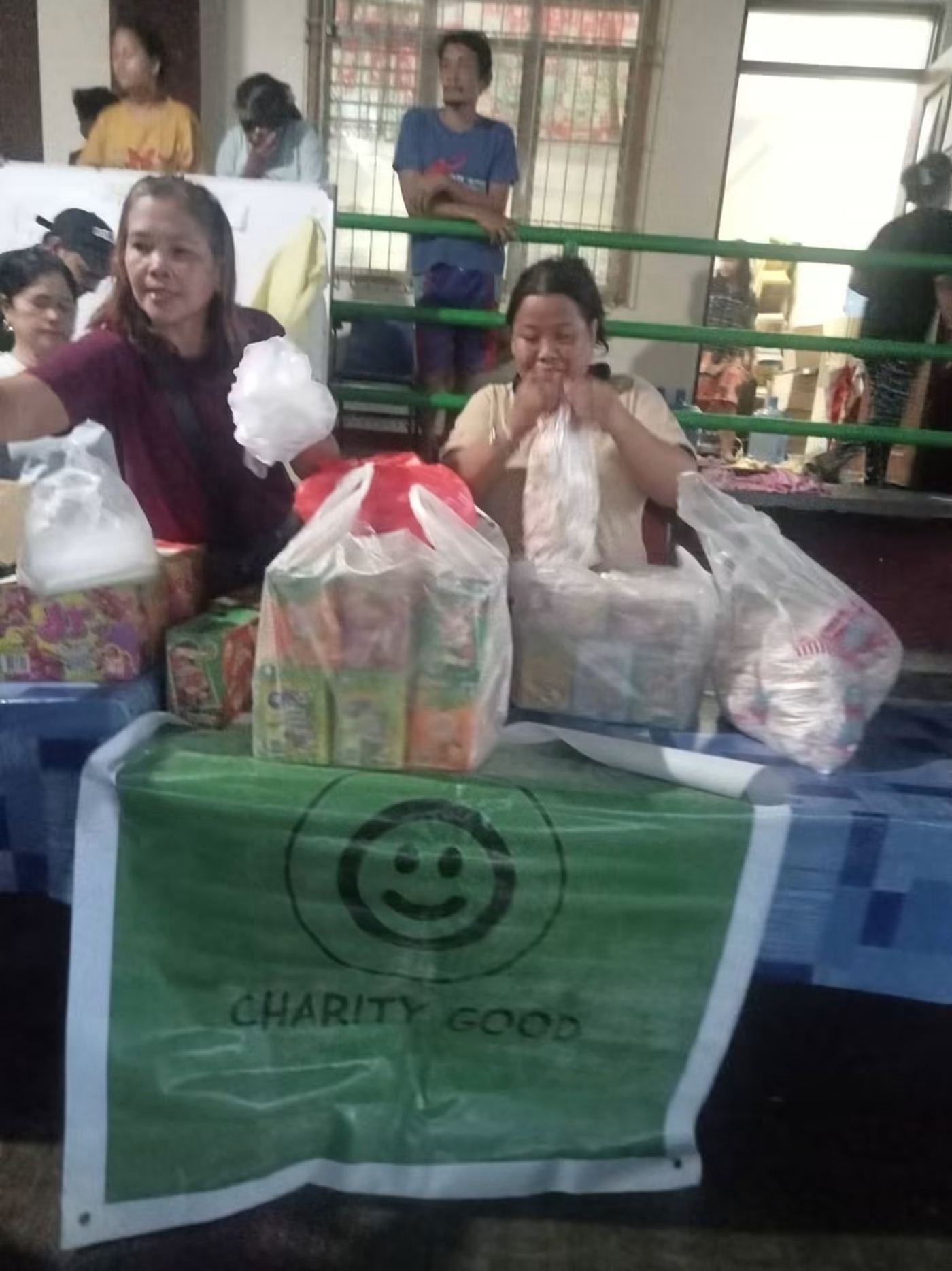A Charity Good banner above a table stacked with food supplies